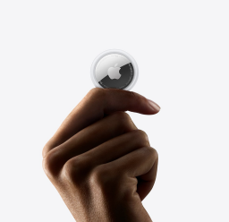 An Apple AirTag held in a person's hand.