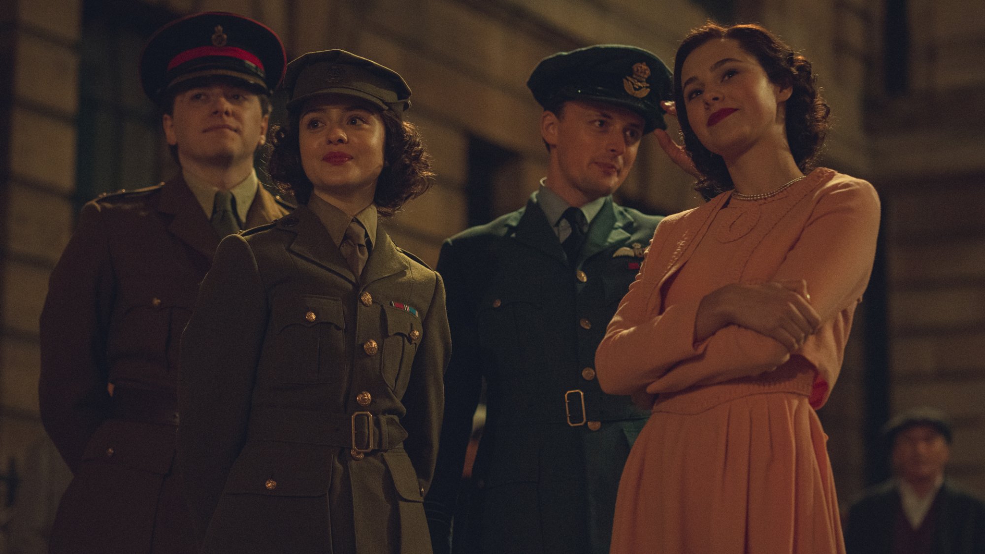 Two young girls and boys in '40s military and evening wear stand together at night