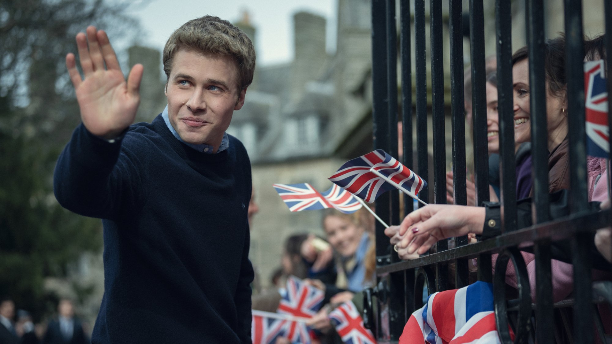 An actor resembling Prince William waves to fans with the Union Jack flag