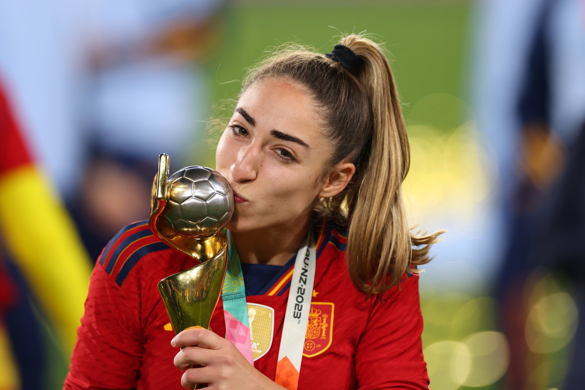 Carmona, in a high ponytail and red jersey, kisses the soccer ball atop the Women's World Cup trophy.