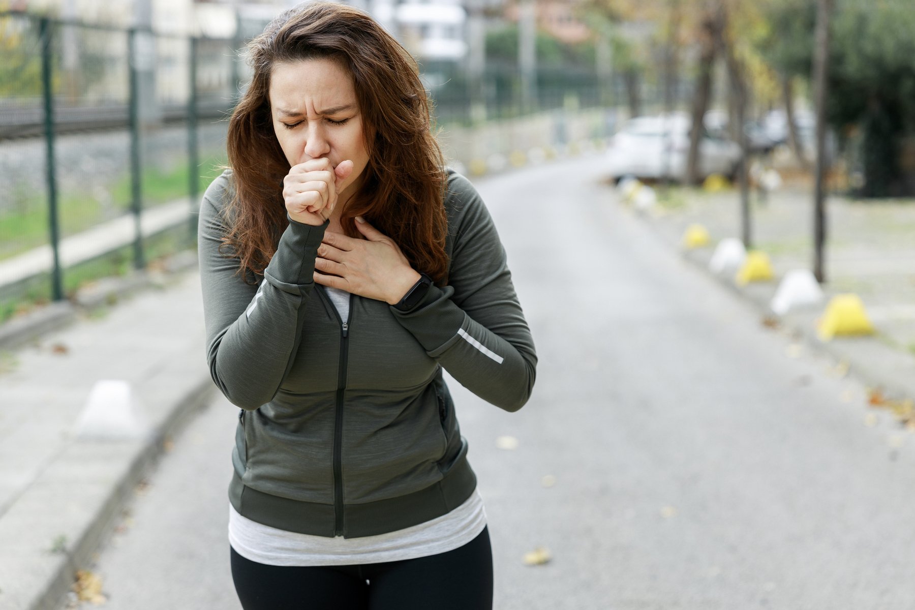 a woman coughing outdoors