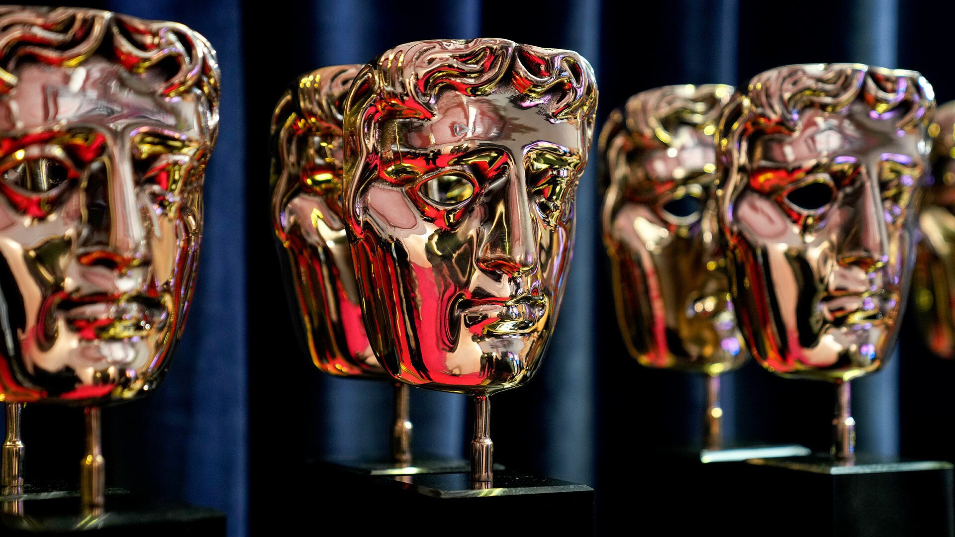 A row of BAFTA golden awards are seen on a shelf.