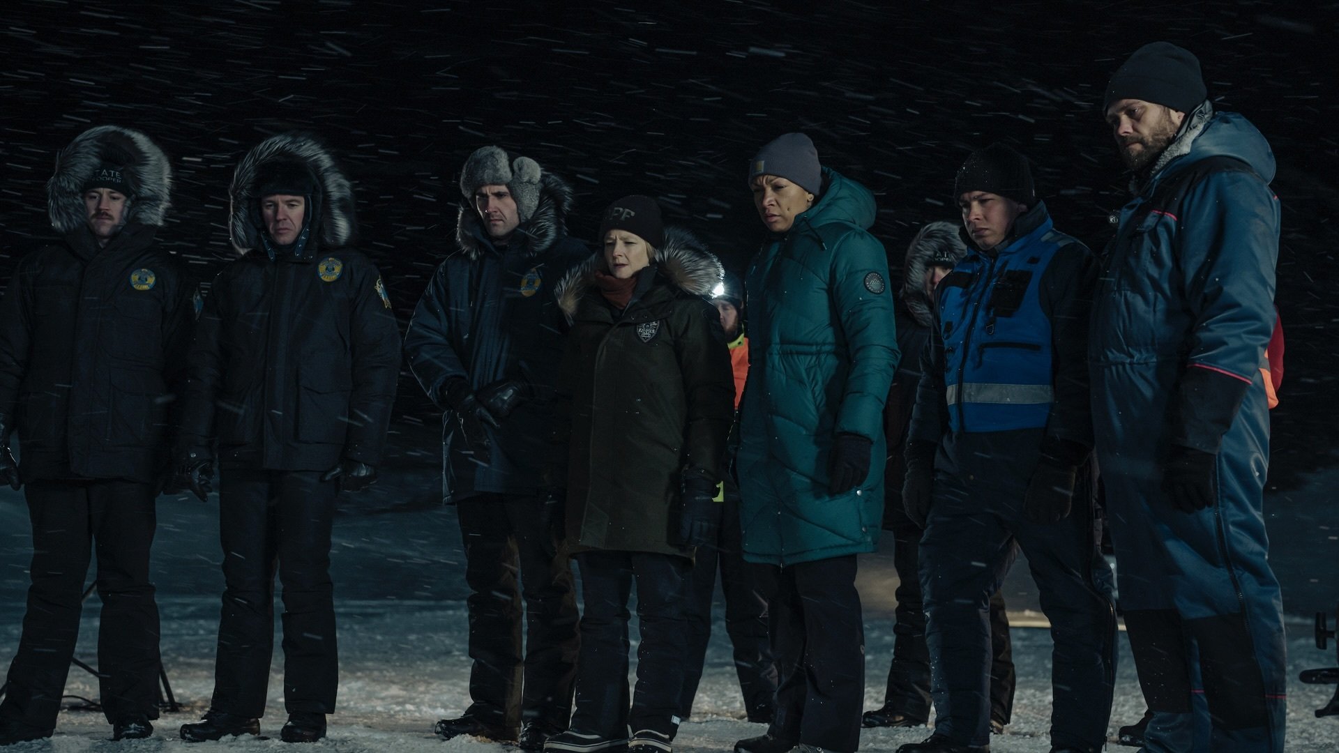 A group of men and women in police uniforms stand in the snow.