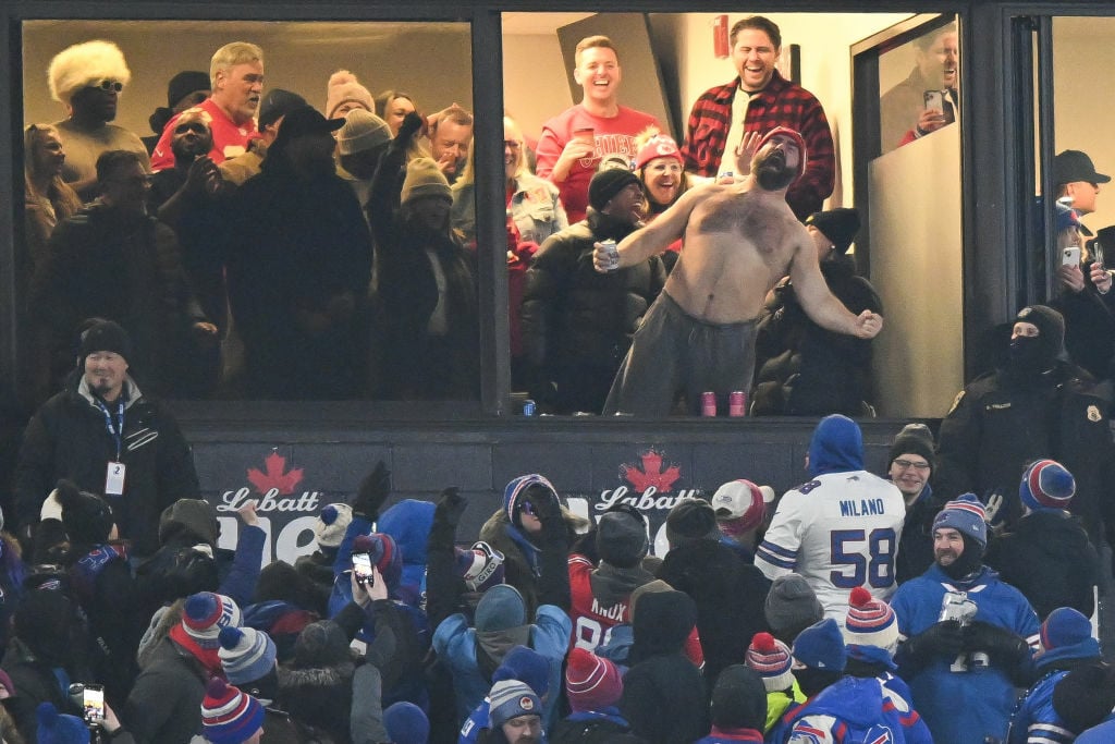 jason kelce, shirtless screaming hanging out of a luxury suite in an nfl stadium