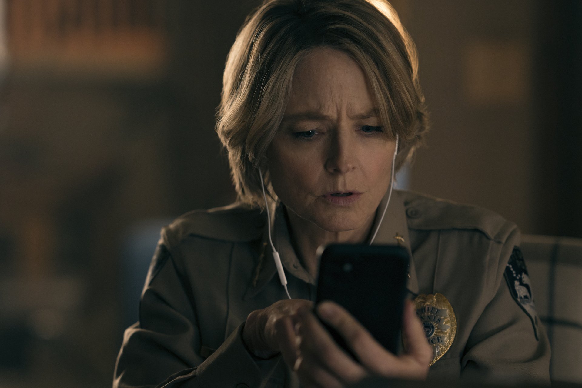 A woman in a police uniform watches something on her phone.