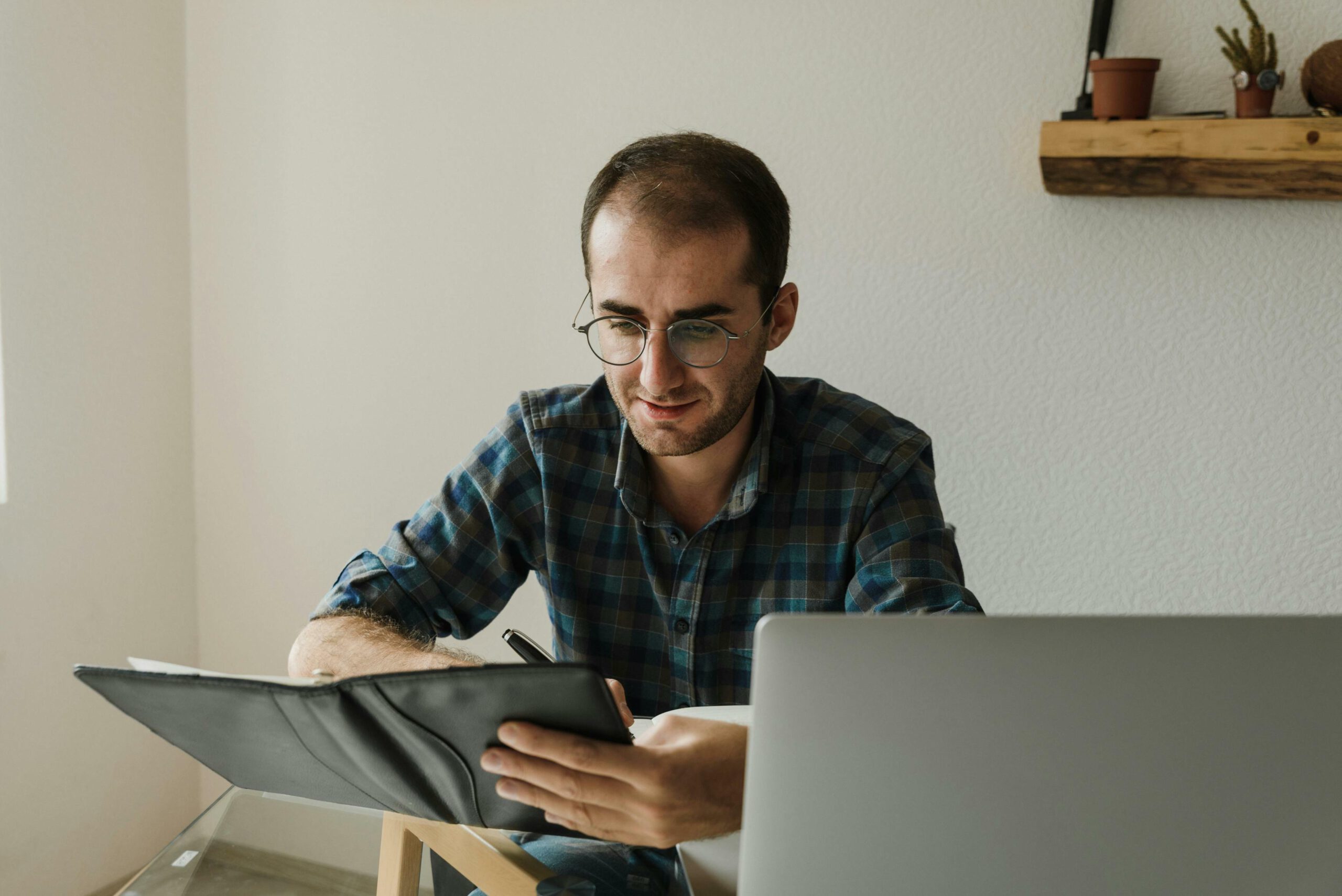 Man writing in book with laptop