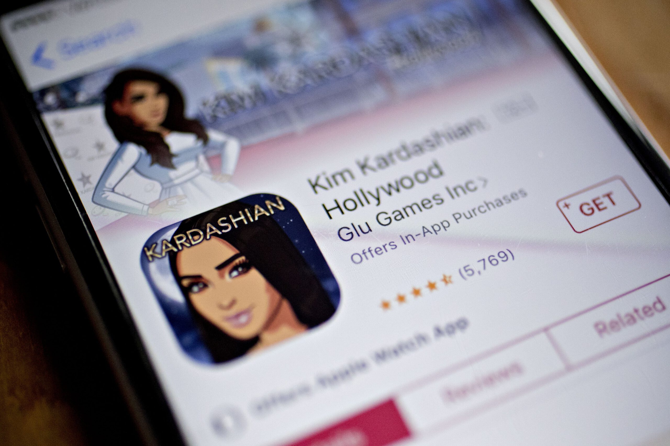 Mobile phone with the Kim Kardashian: Hollywood app store listing on it.