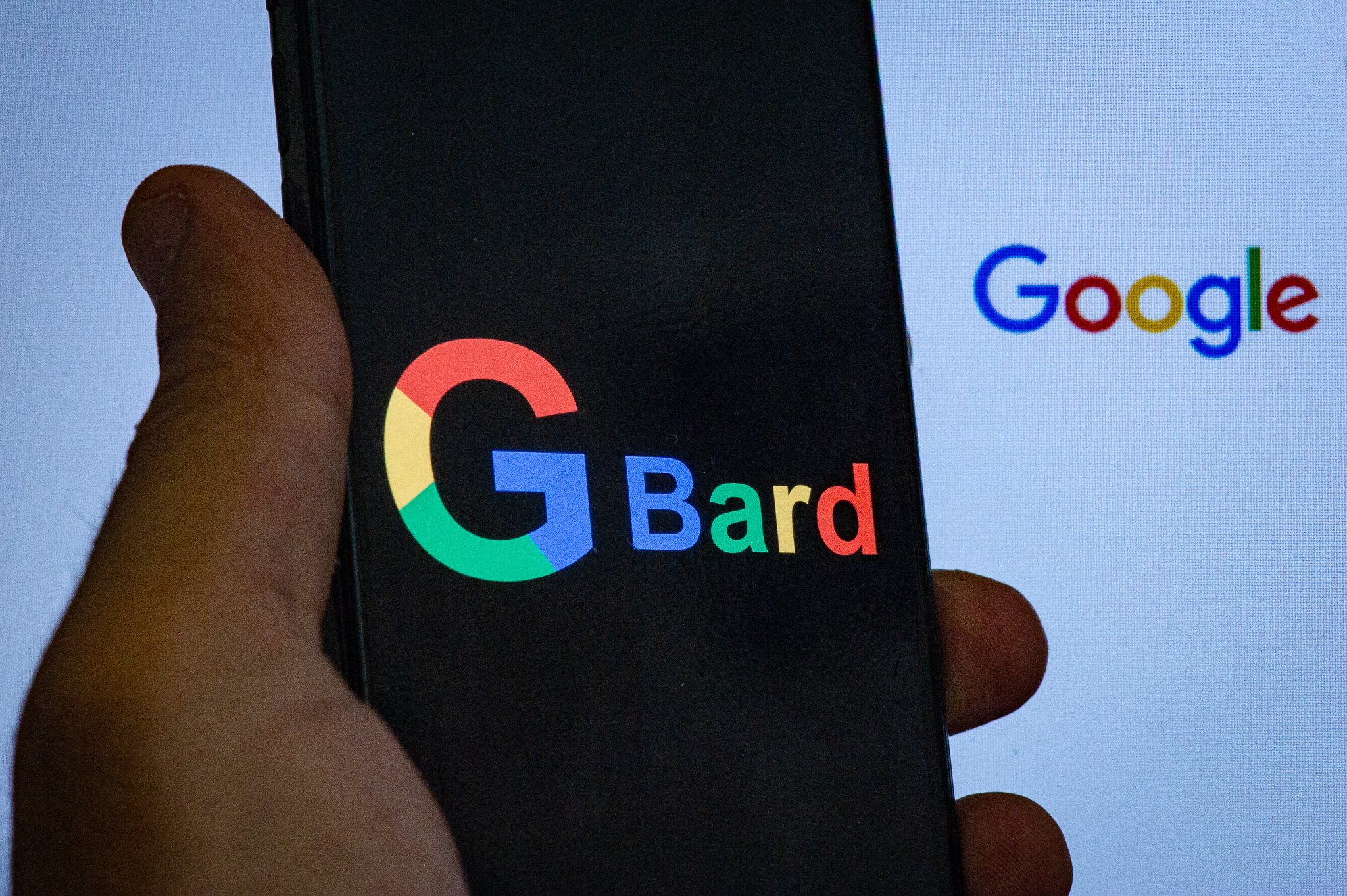 A Google logo displayed on a personal computer and a Bard logo displayed on a mobile phone 