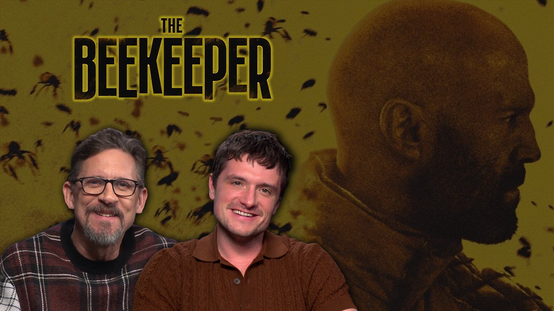 osh Hutcherson and David Ayer smile at the camera. A giant yellow poster of the 'Beekeeper' with a close up of Jason Statham standing among a swarm of bees is their background.