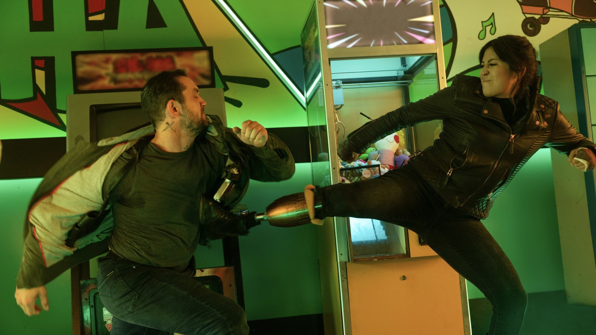 Maya Lopez kicks a man while fighting in an arcade.