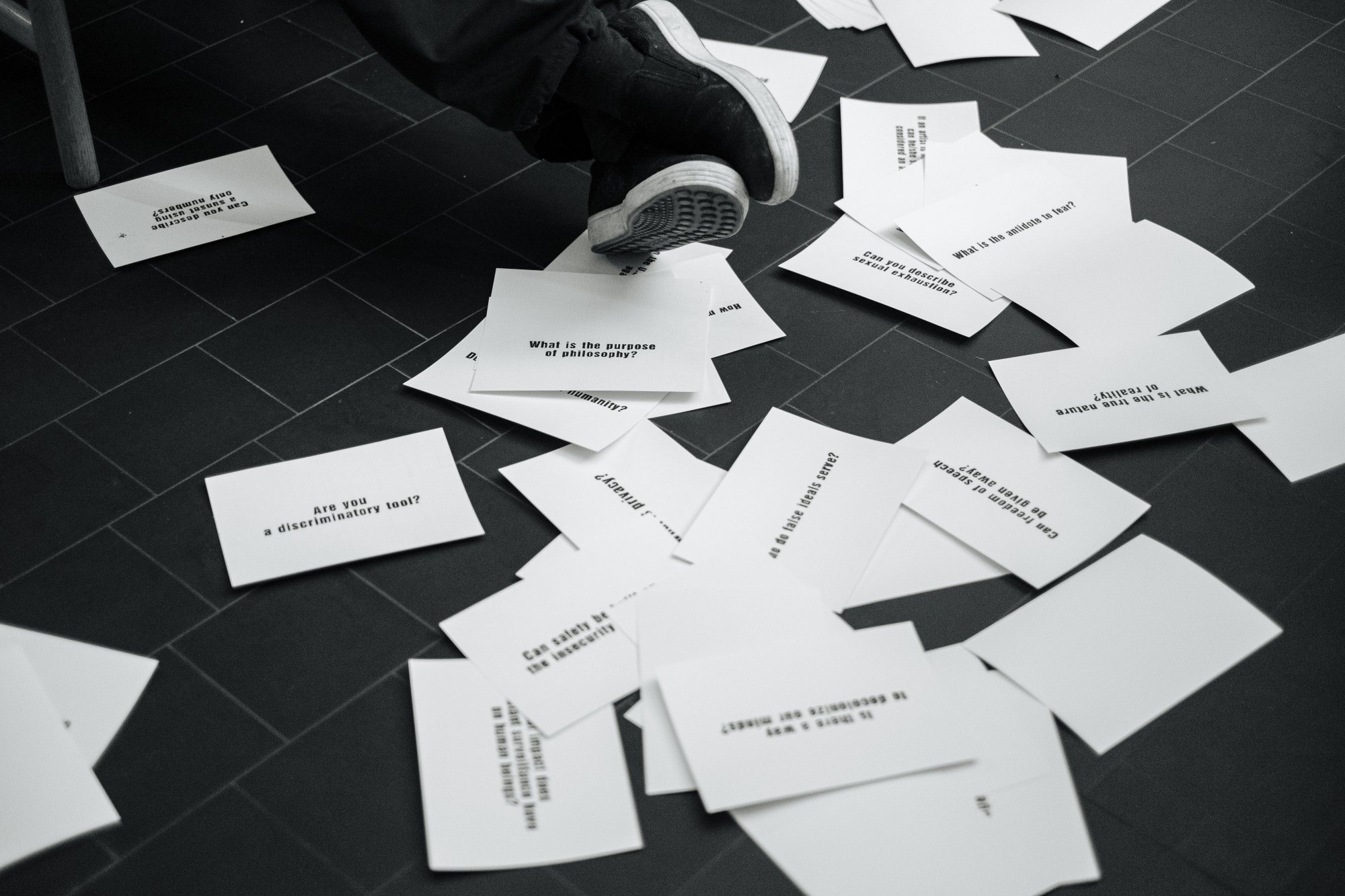 Loose papers on a floor presenting questions by Ai Weiwei.