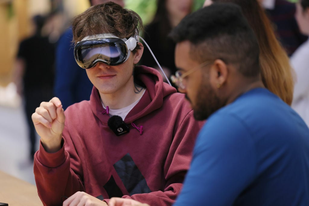 man wearing an Apple Vision Pro and making a hand gesture to execute a task on the device