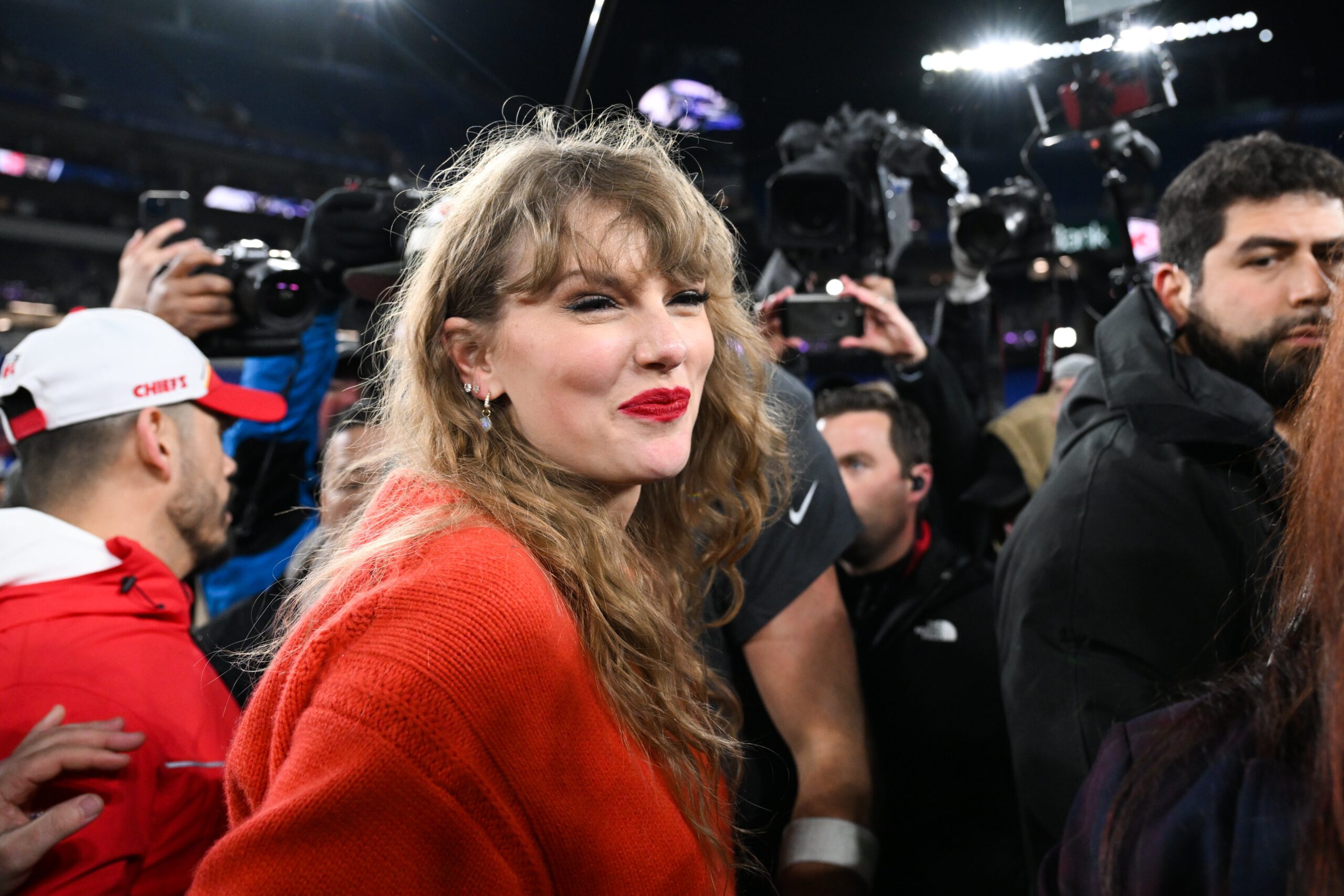 Taylor Swift in a red sweater on the field celebrating the Kansas City Cheifs' win.
