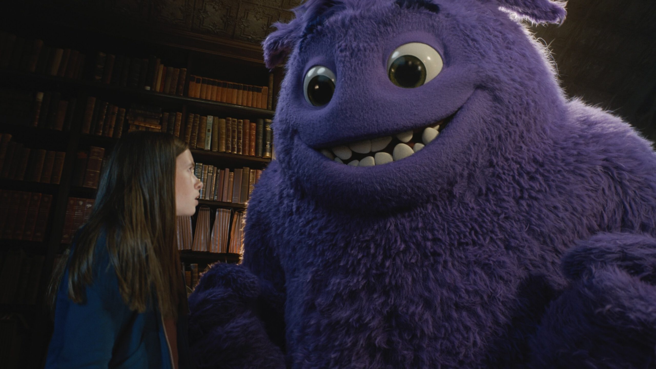A large, fluffy, purple creature smiles at a young girl.