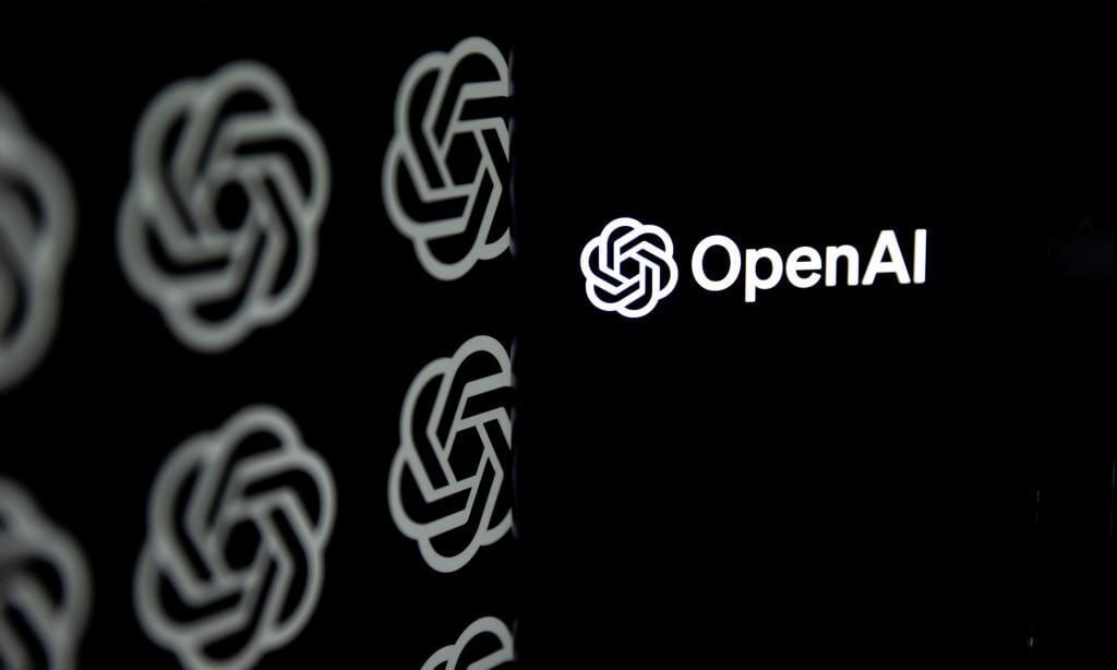 OpenAI logo is being displayed on a mobile phone screen in front of computer screen with the logo of ChatGPT.