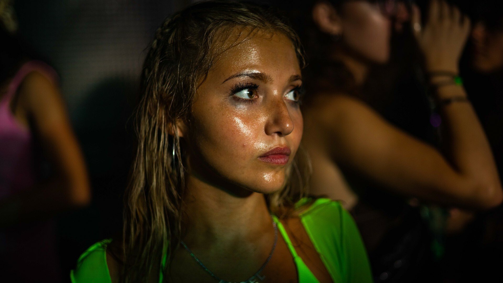 A teen girl looks deeply serious at a party.