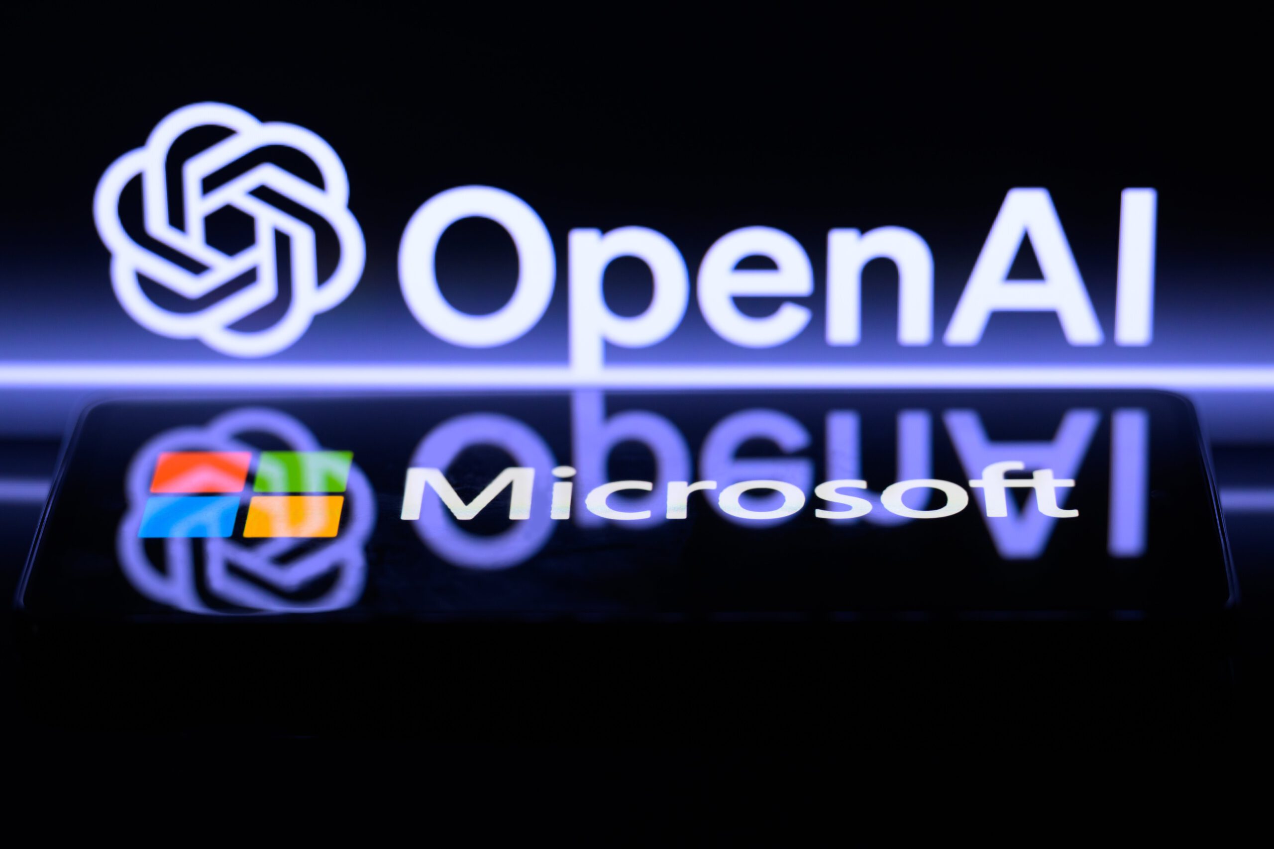 The OpenAI and Microsoft logos reflecting each other on a dark screen.