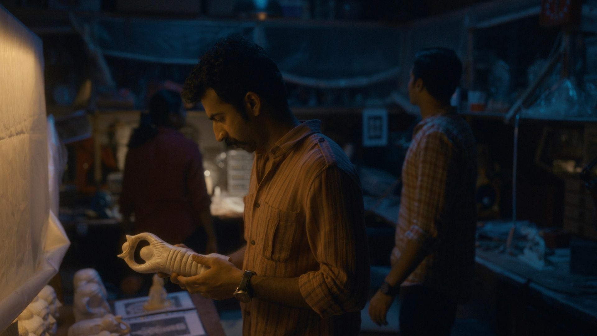 Actor Roshan Mathew holding an object made of ivory in a still from 'Poacher'.