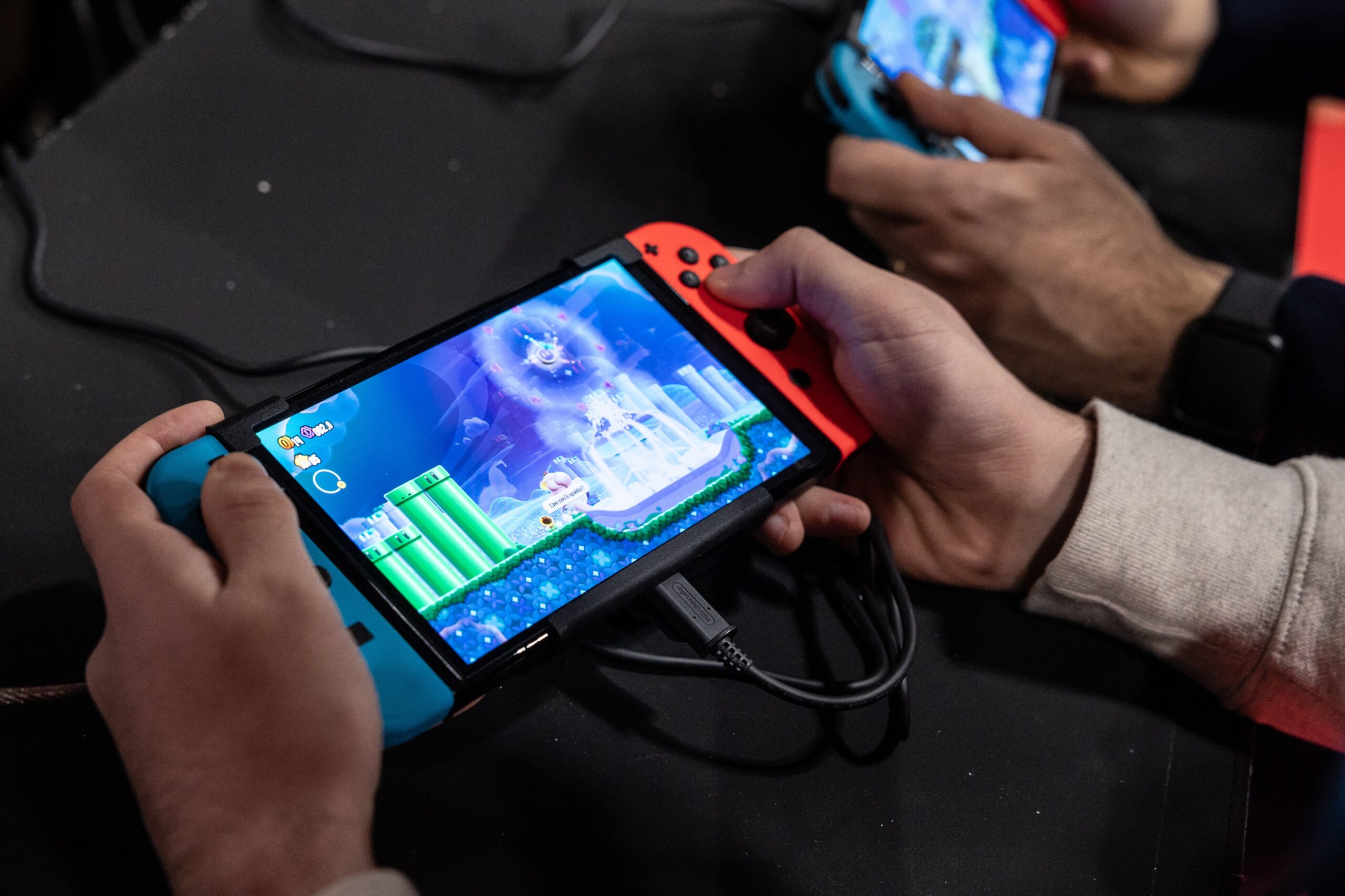 Two men use an Oled model Nintendo Switch gaming system while playing video games at the Japanese publisher Nintendo Switch's stand during Milan Games Week 2023