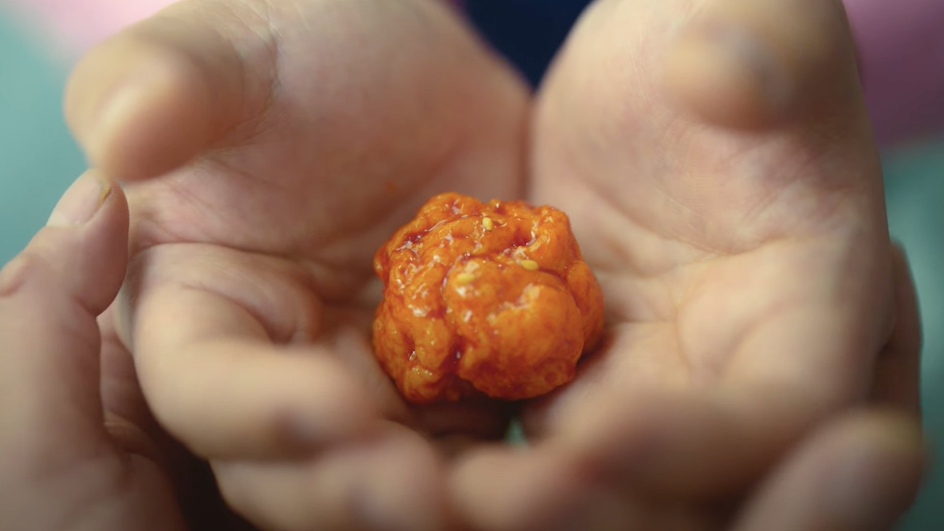 A chicken nugget rests in a man's hands.
