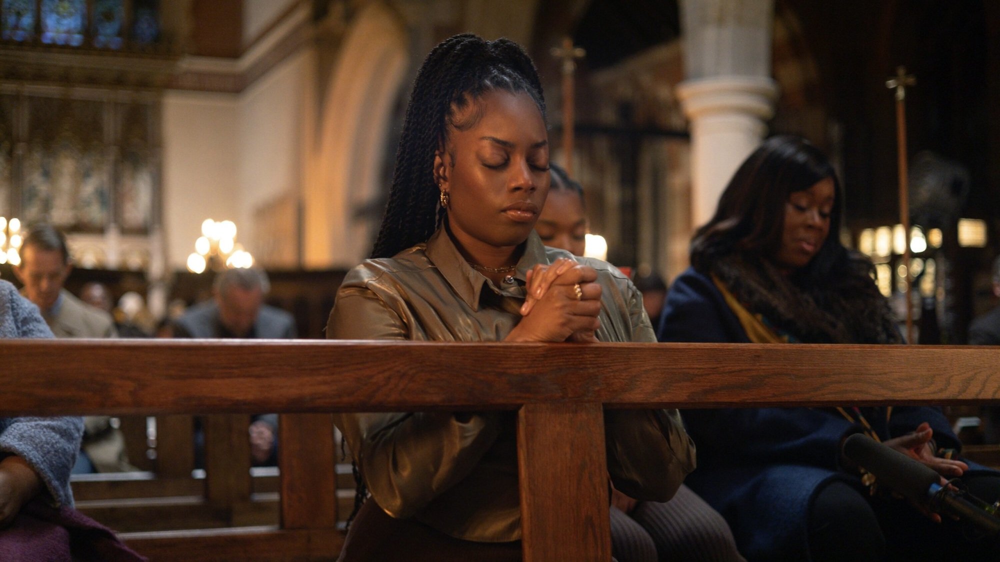 A young woman praying in a church pew.