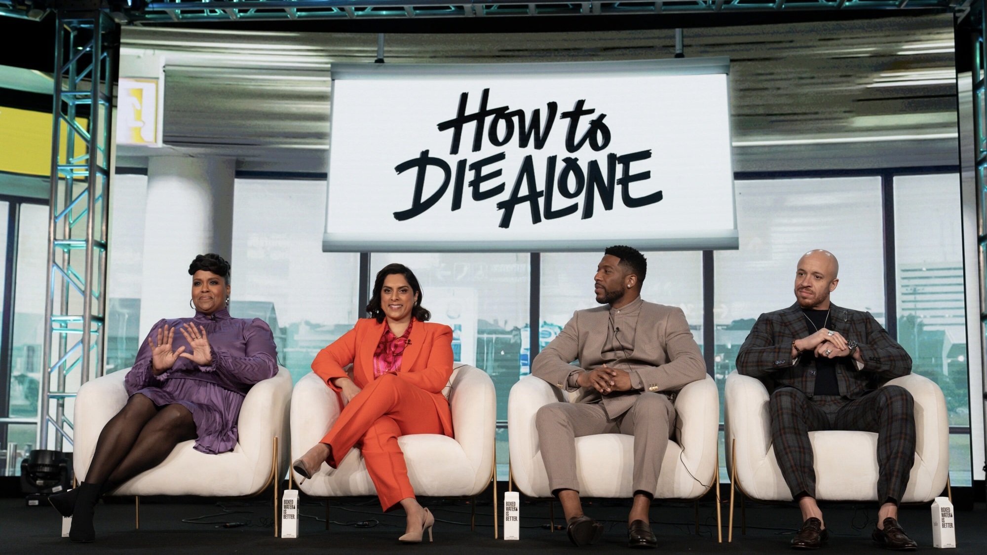 The cast and creators of "How to Die Alone" sit onstage at a press event.