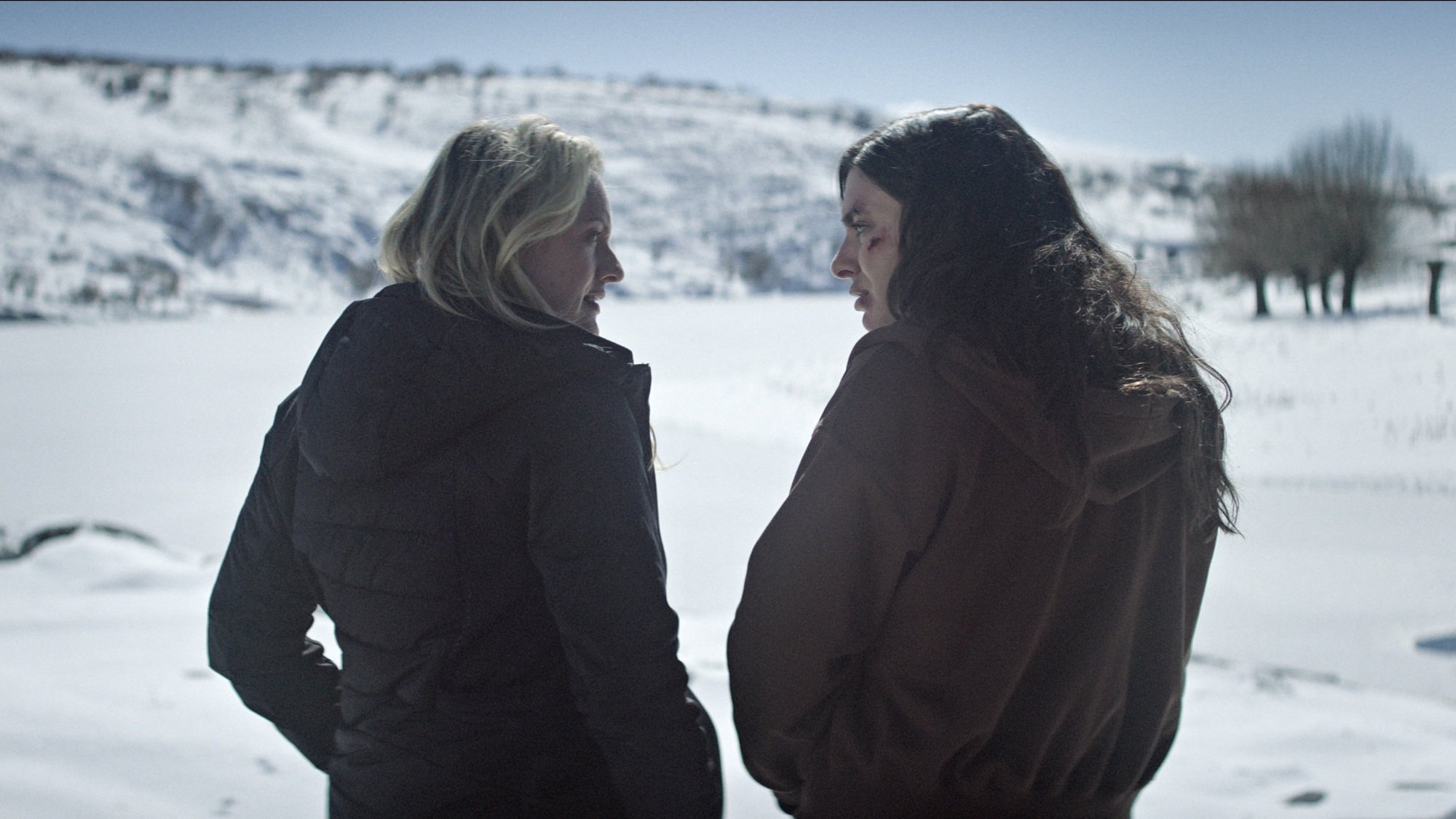 Two woman talking while in a vast snowy plain.