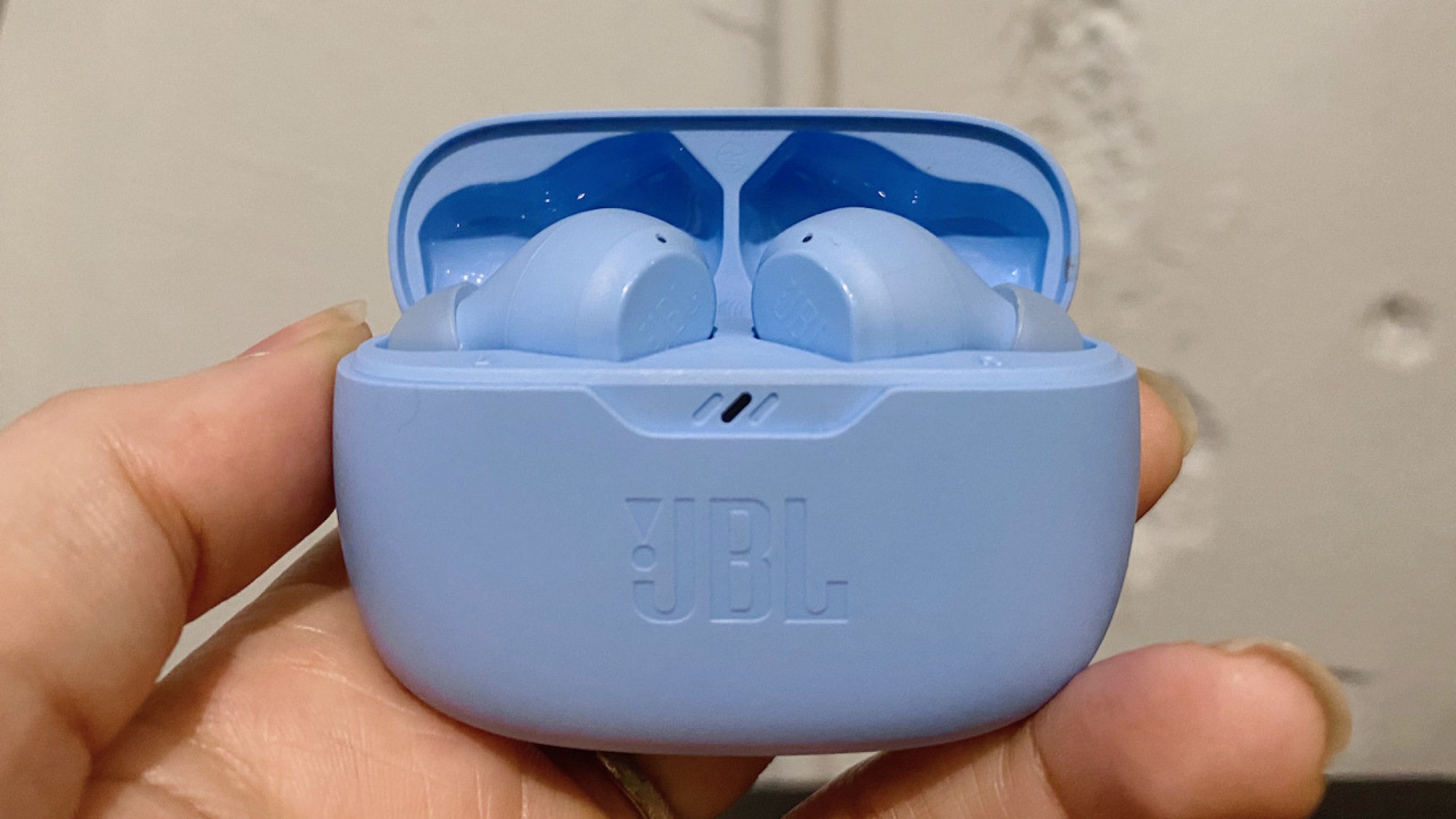 close-up of jbl vibe beam earbuds charging case in hand