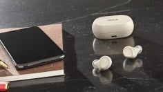 jabra elite 7 pro earbuds on a table next to a phone and notebook