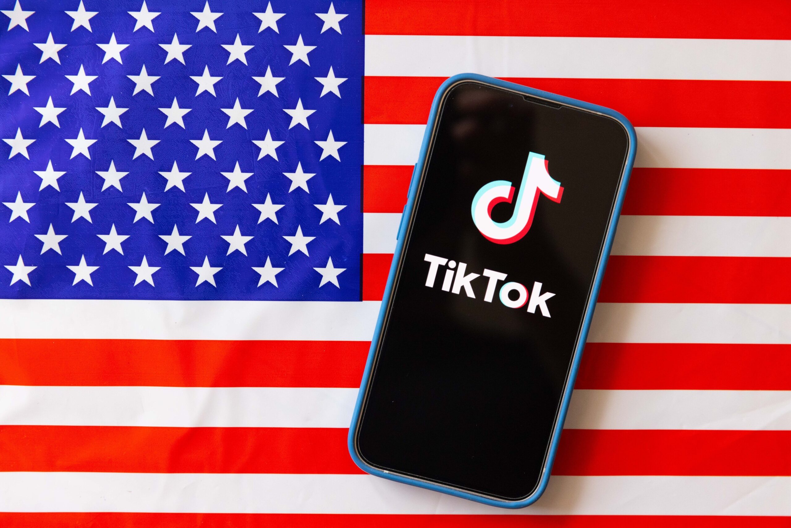 TIkTok logo on mobile phone with the American flag in the background.