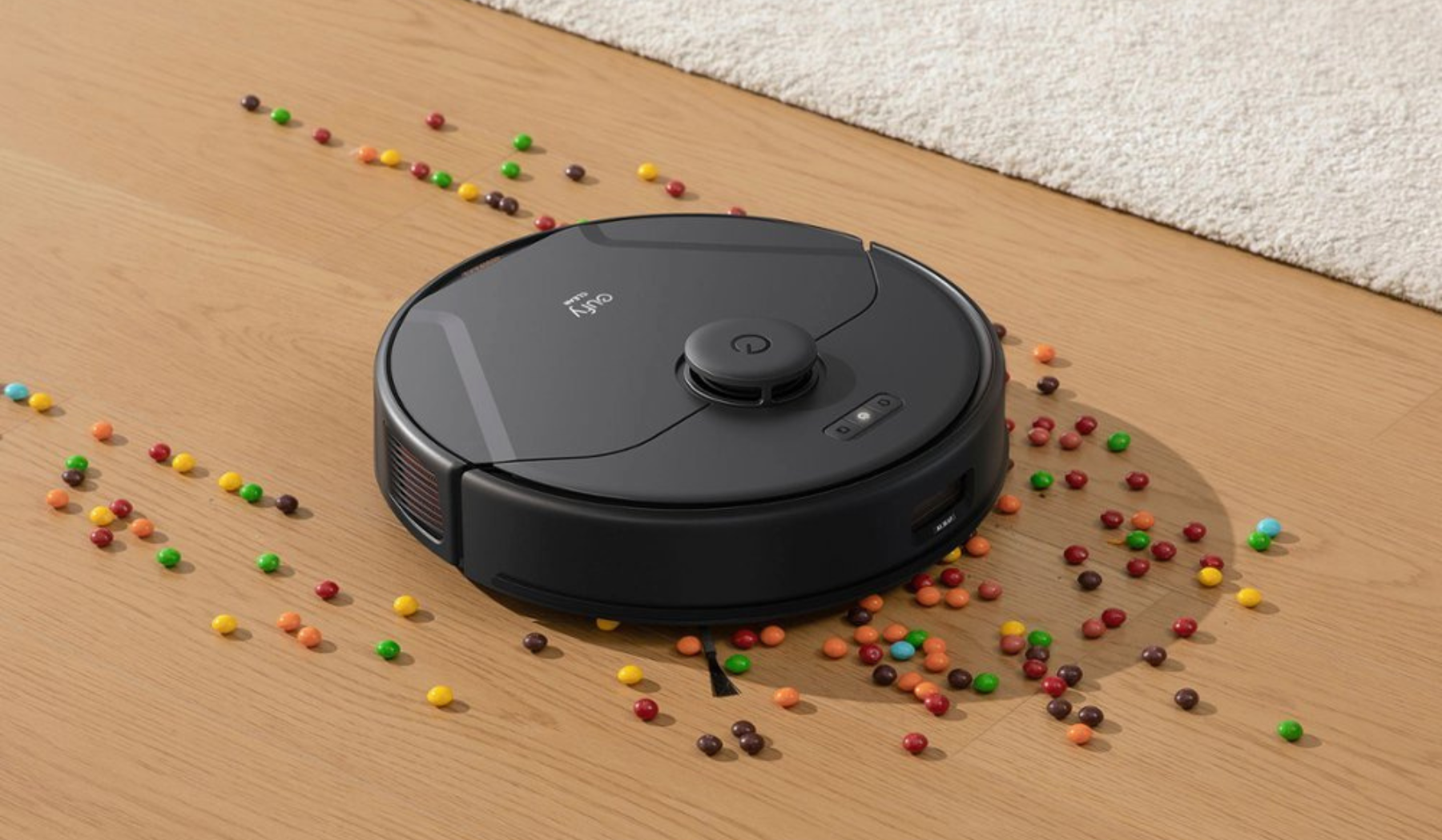 Eufy robot vacuum cleaning candy on hardwood floor with rug in background