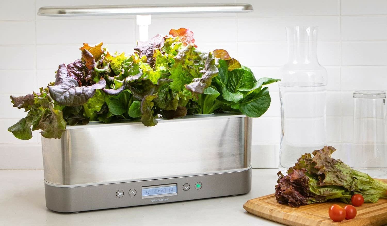 an aerogarden sits on a kitchen counter with a cutting board next to it with lettuce and tomatoes 