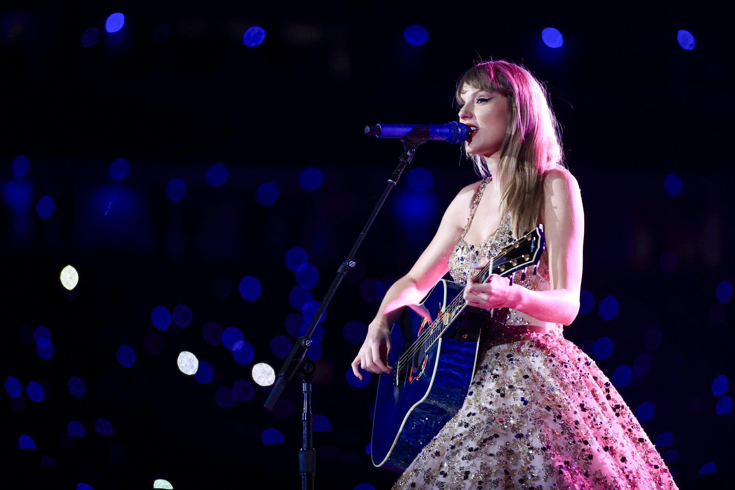 Taylor Swift performing with her guitar on stage at The Eras Tour