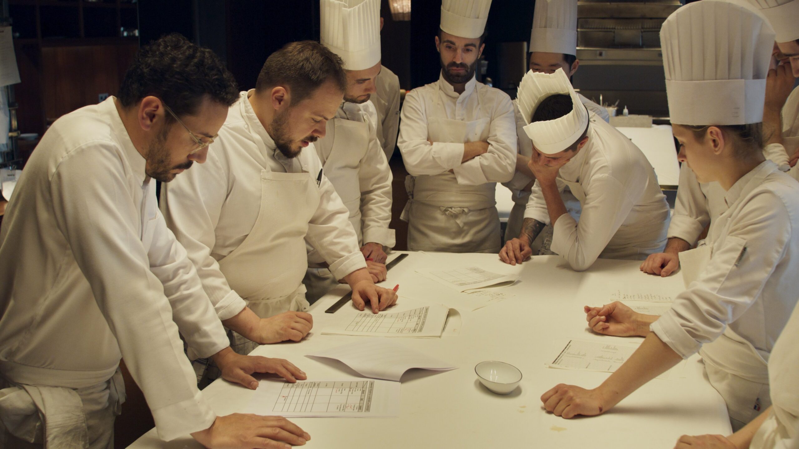 A group of chefs gather around a table.
