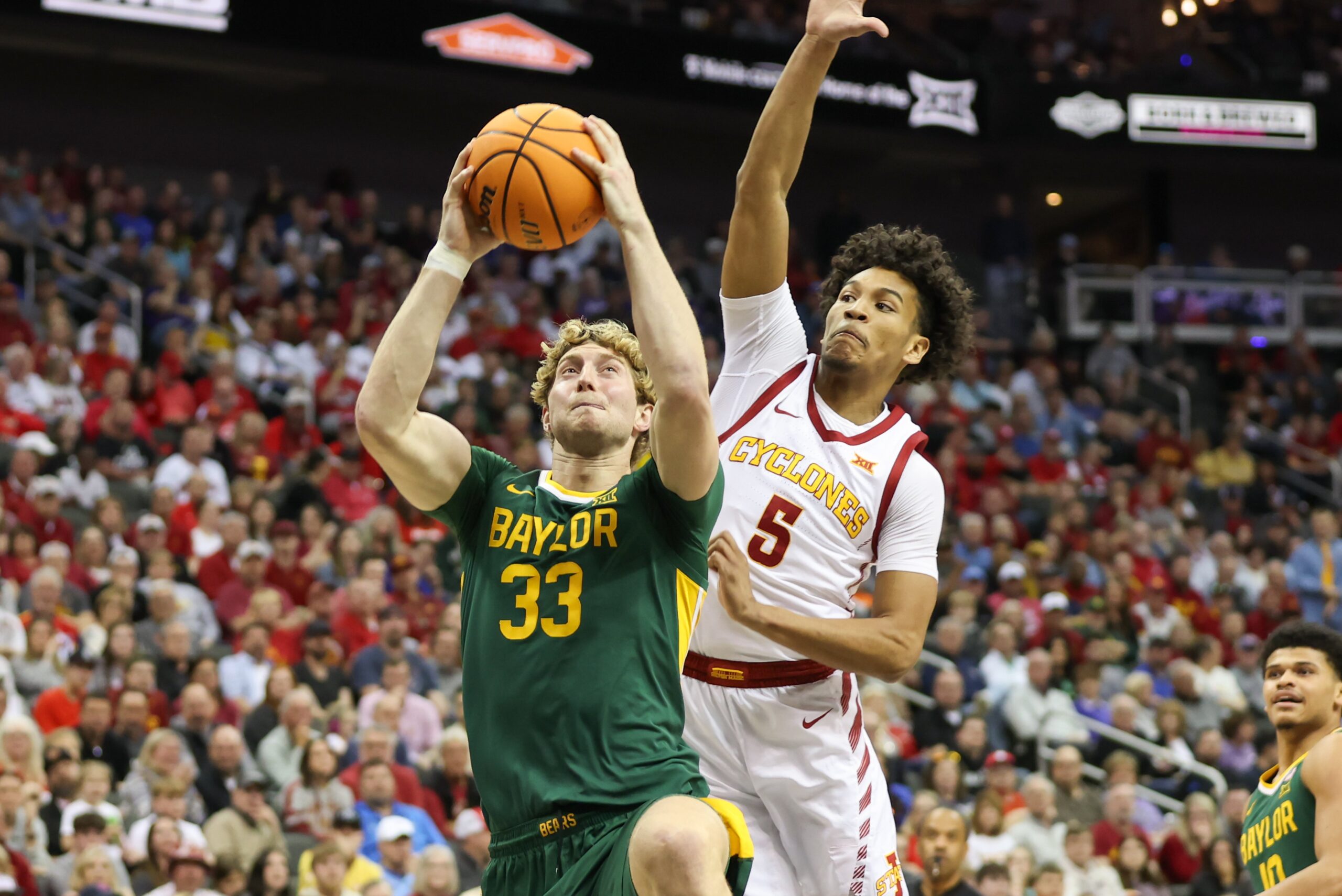 Baylor Bears forward Caleb Lohner (33) drives to the basket as Iowa State Cyclones guard Curtis Jones (5) tries to block the shot in the first half of a Big 12 tournament semifinal game between the Baylor Bears and Iowa State Cyclones on March 15, 2024, at T-Mobile Center in Kansas City, Missouri. 