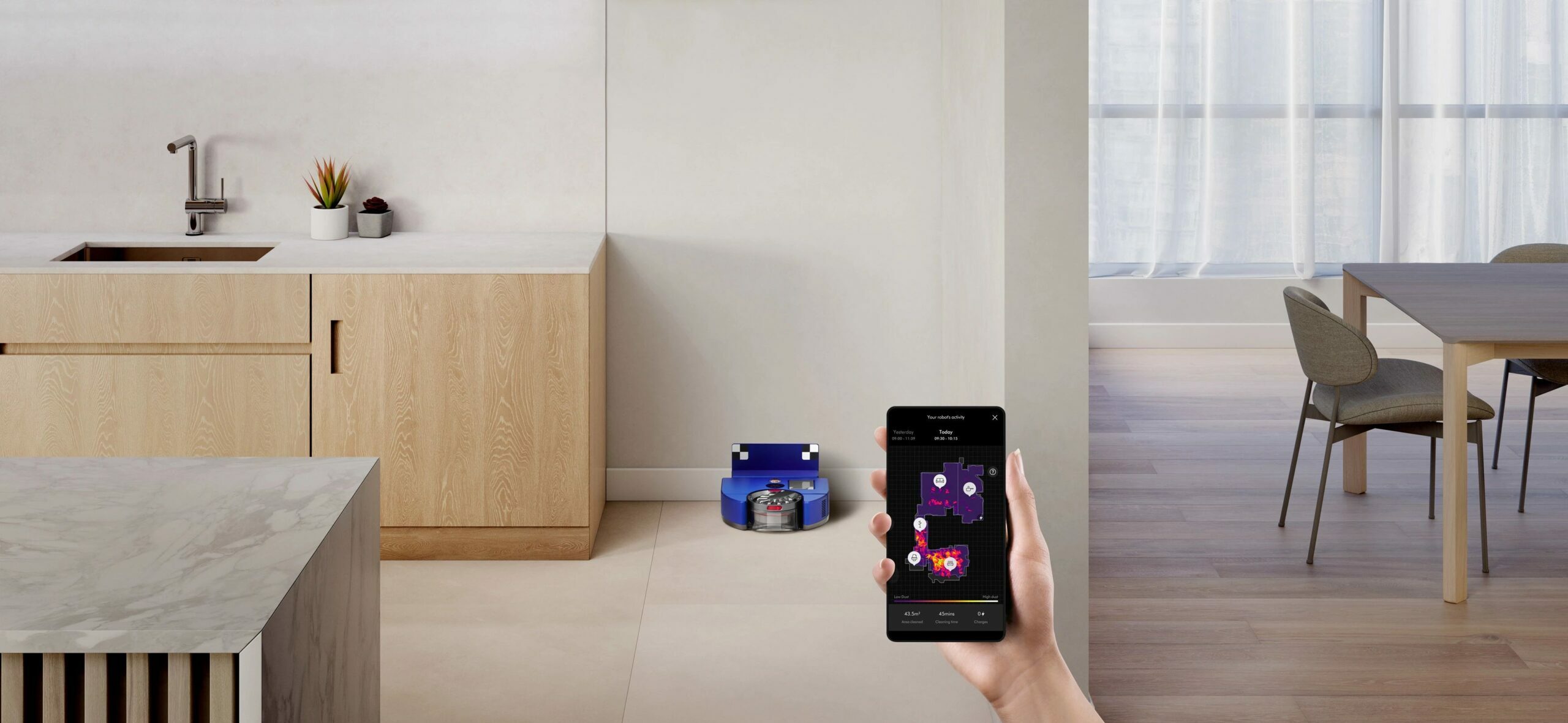 Dyson 360 Vis Nav robot vacuum and dock sitting against wall in kitchen with counter and dining table in peripherals