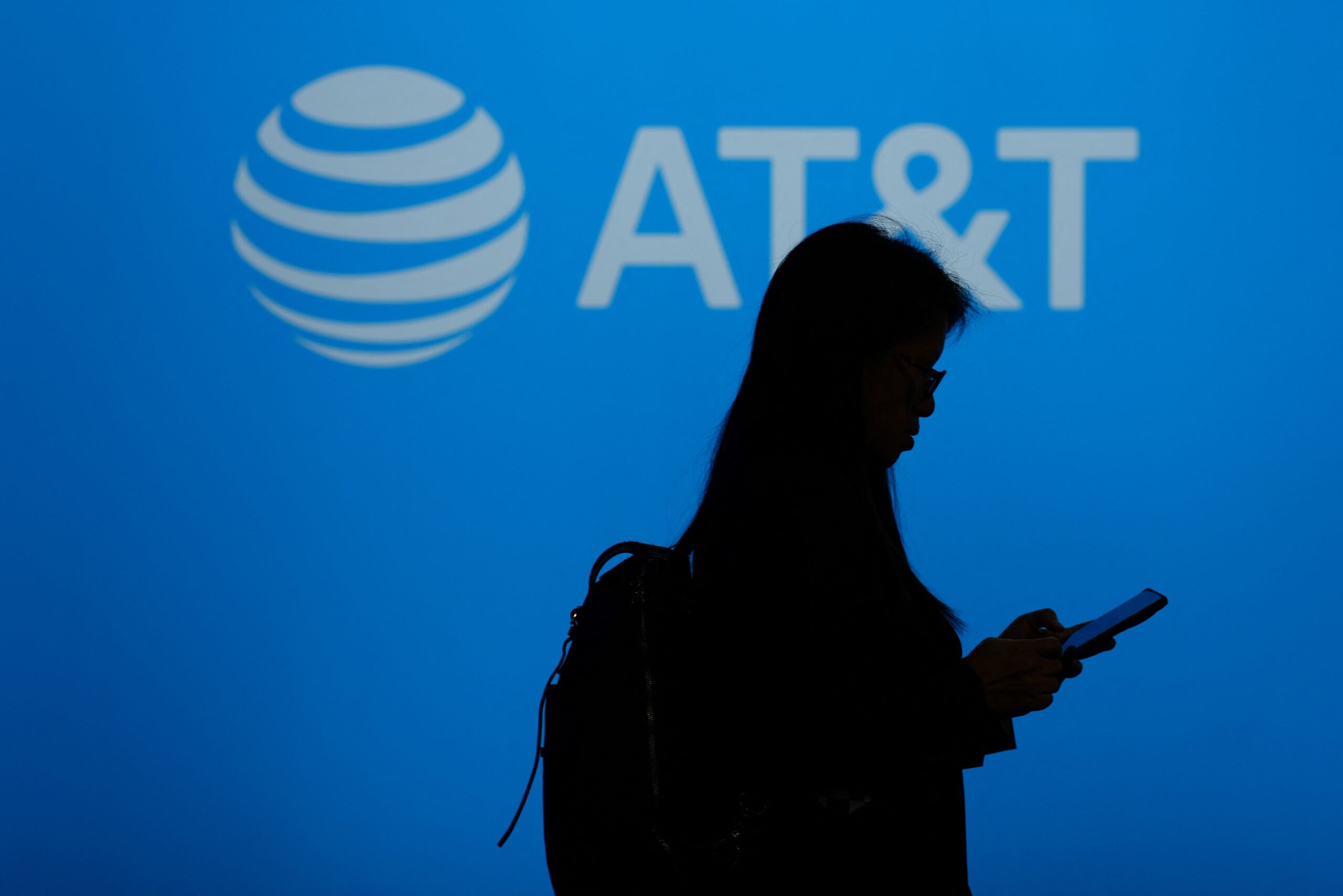 A visitor walks past US multinational telecommunications AT&T logo during the Mobile World Congress (MWC), the telecom industry's biggest annual gathering, in Barcelona on February 26, 2024. The world's biggest mobile phone fair throws open its doors in Barcelona with the sector looking to artificial intelligence to try and reverse declining sales.