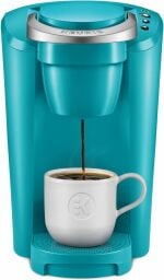 a turquoise Keurig machine with a white mug receiving coffee on a white background