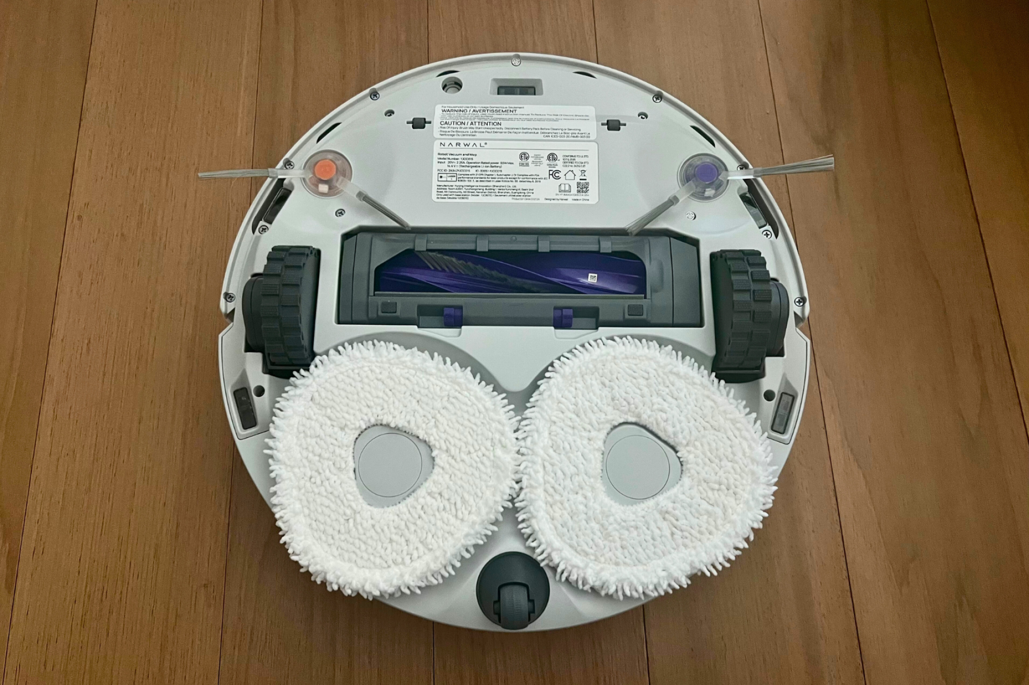 Underside of Narwal robot vacuum featuring two mopping pads and brushroll
