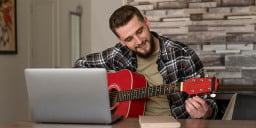 man doing online lesson with guitar