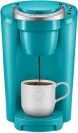 a turquoise Keurig machine with a white mug receiving coffee on a white background