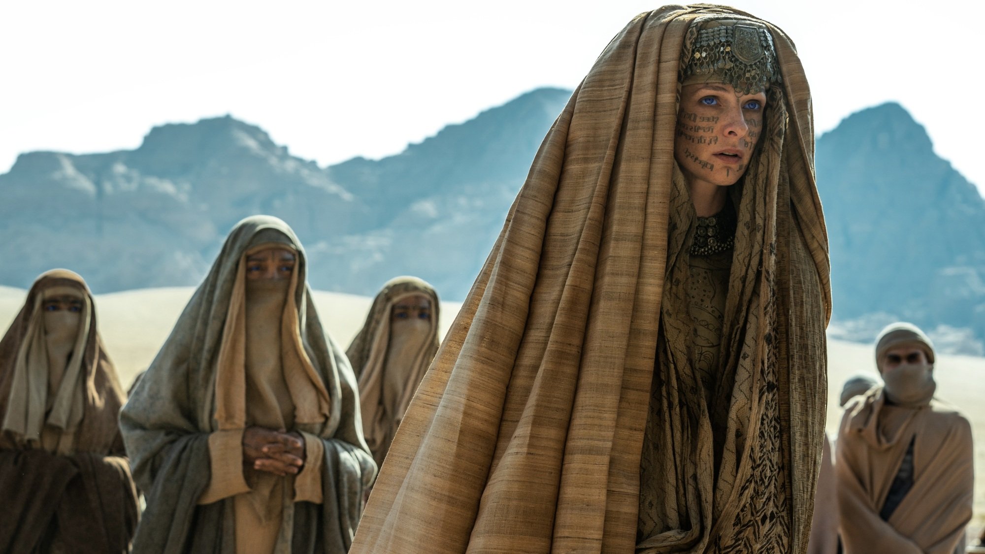 Lady Jessica and her Fremen followers walk through the desert, wearing head coverings.