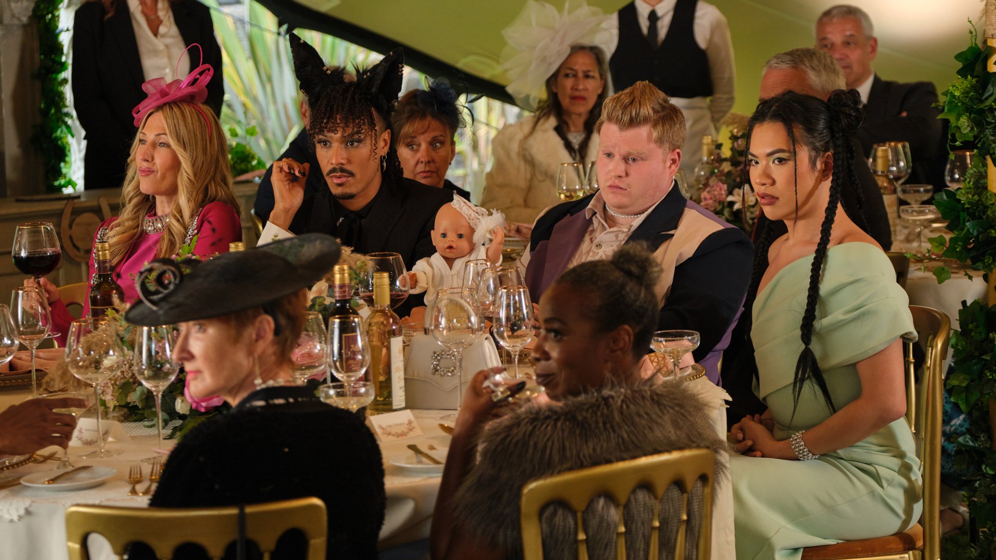 A group sit at an opulent table at a wedding. 