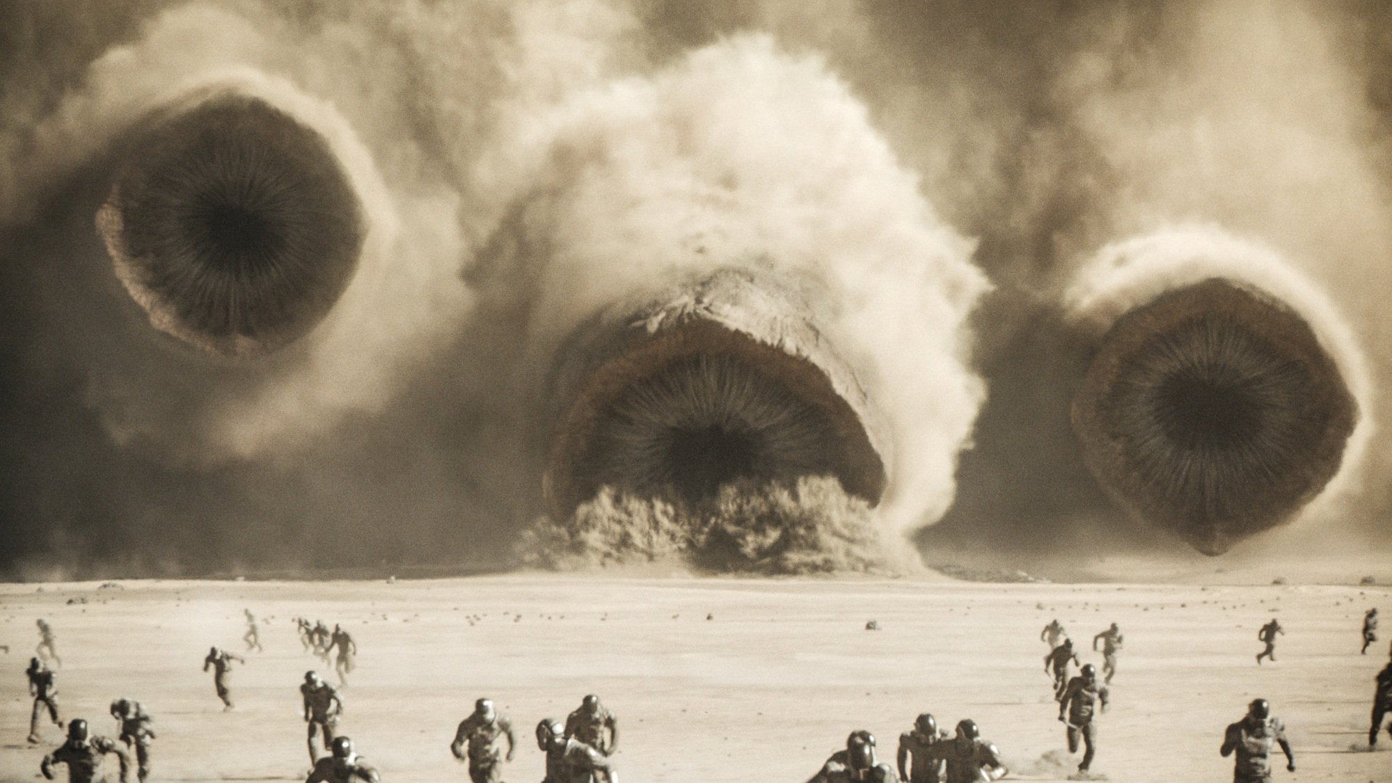 Three sandworms barrel towards an army of humans.