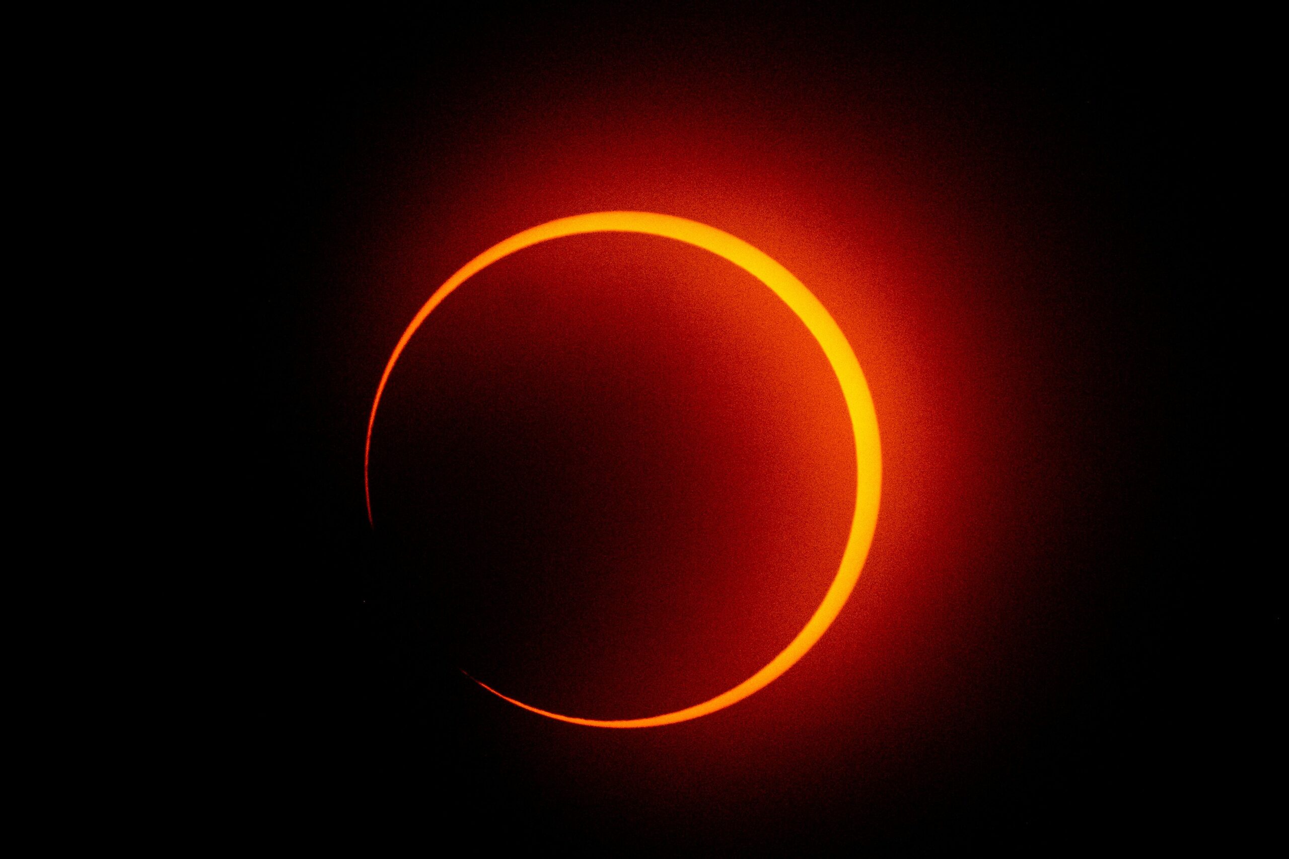 A glowing red outline of the eclipse on a pitch black sky.
