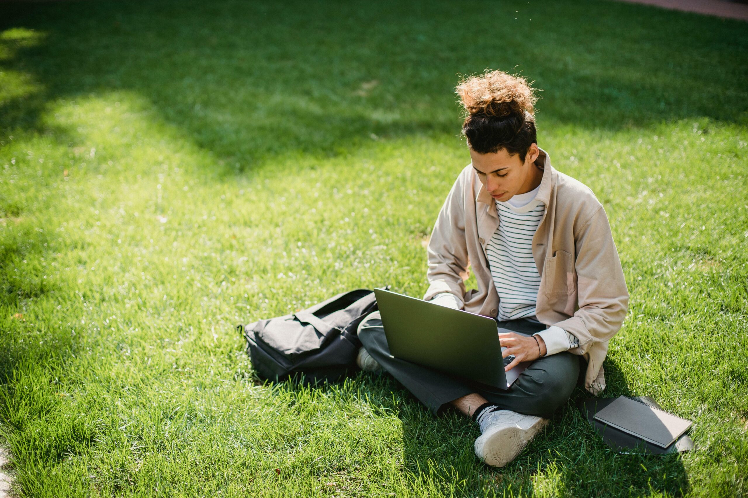Student on lawn using laptop