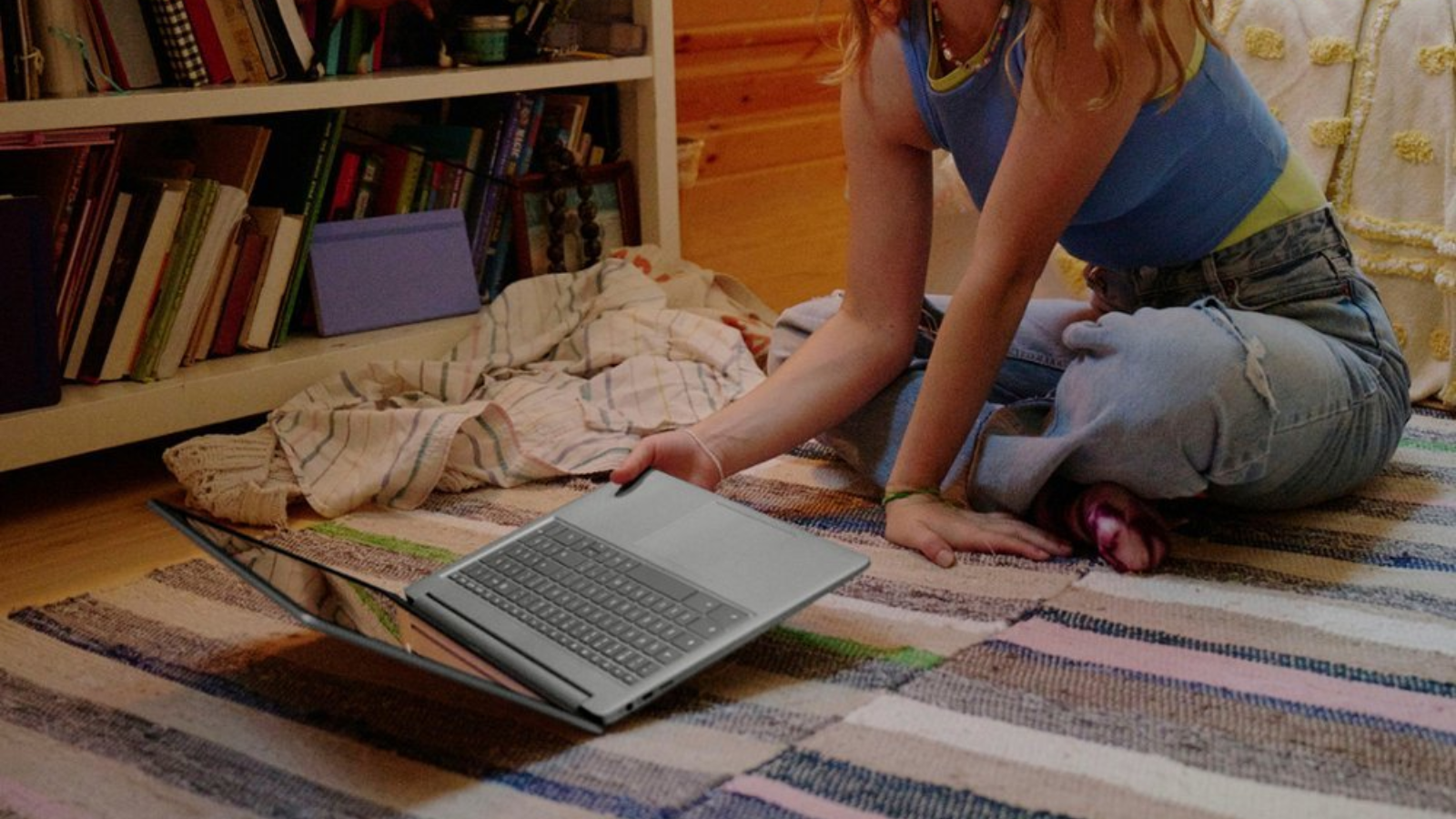 a close-up of a woman picking up an hp chromebook plus 15.6-inch off the floor