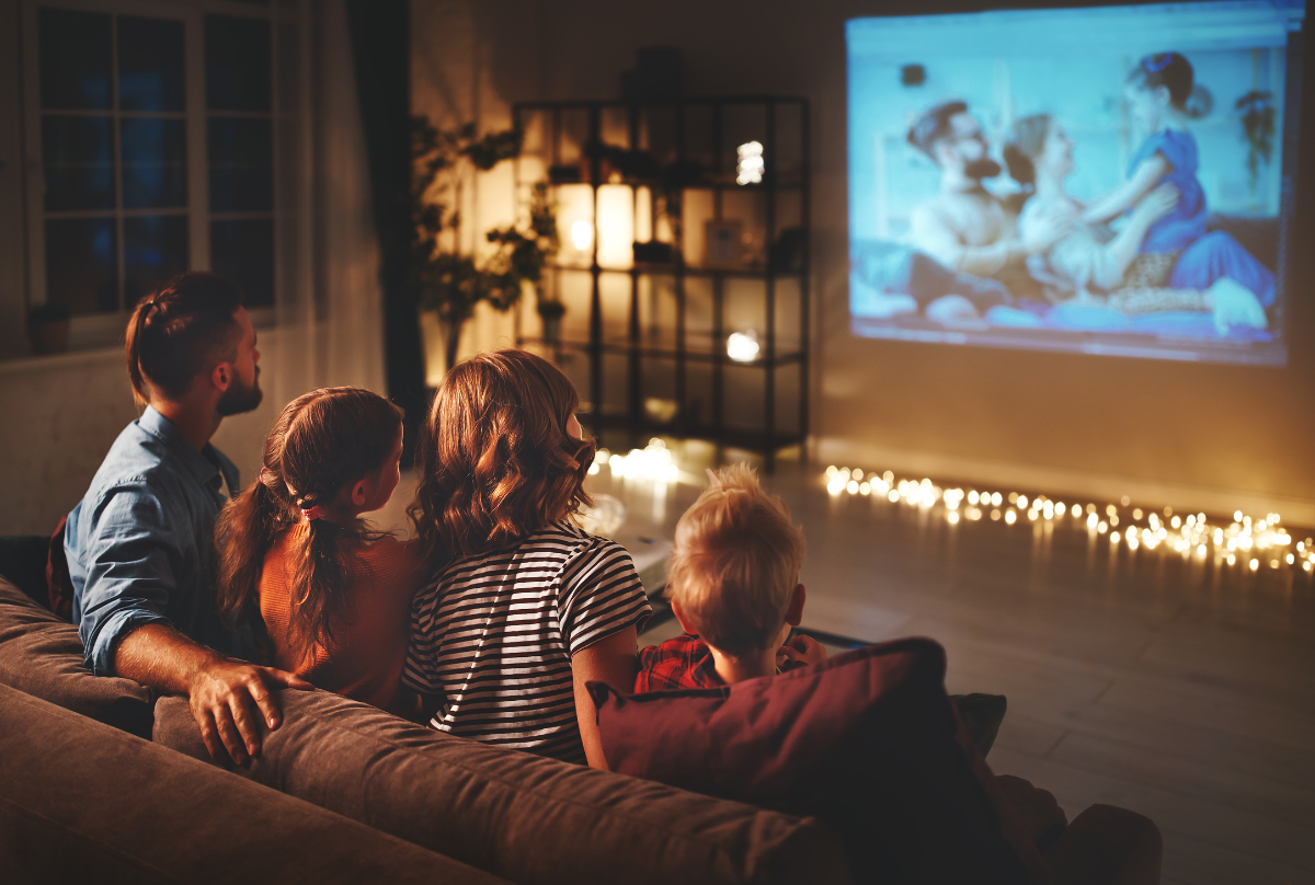 family mother father and children watching projector, TV, movies with popcorn in the evening   at home 