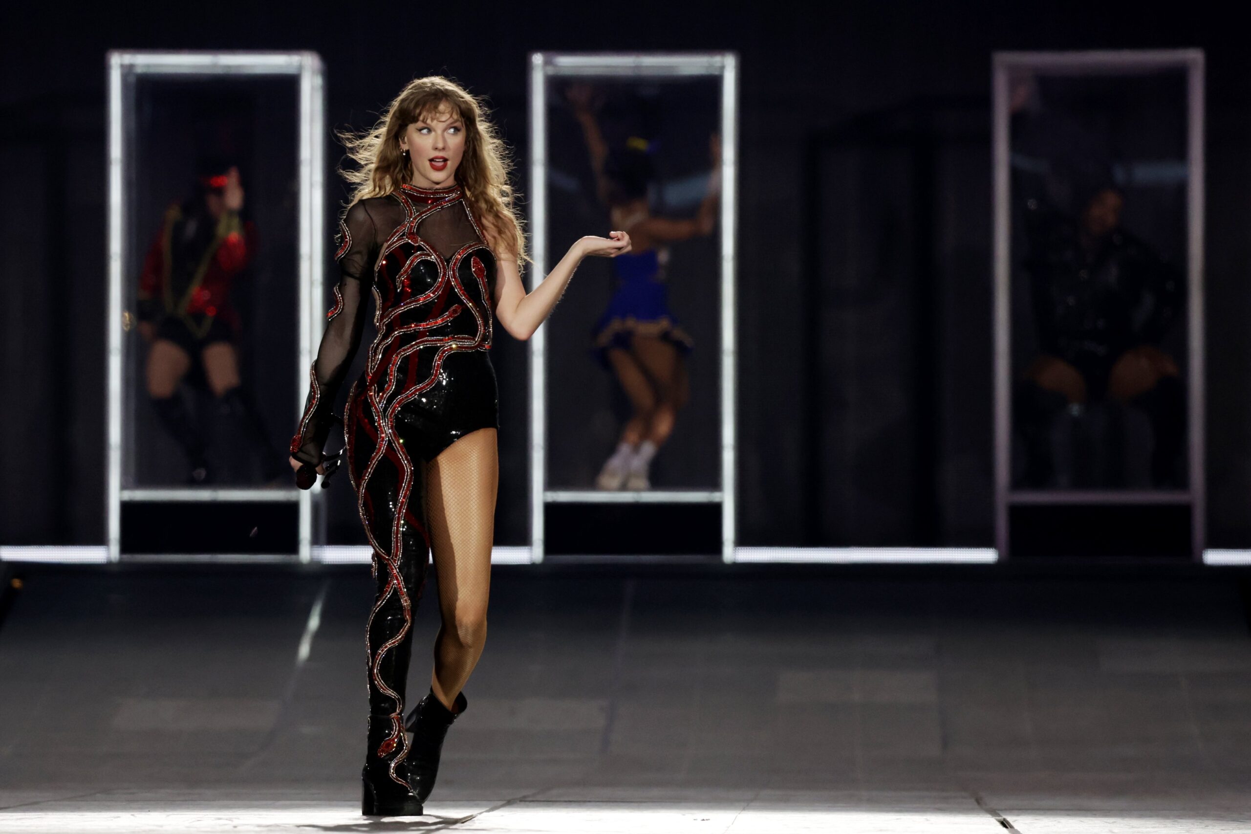 Taylor Swift performing at the Eras Tour in a black jumpsuit.