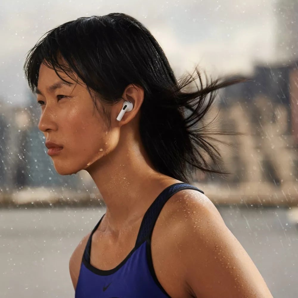 a person wears the apple airpods while working out outdoors and showing visible perspiration